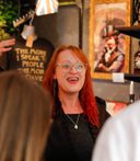 A costumed guide at Villains Rum of York leads a rum tasting inside a dimly lit shop filled with vintage decor and bottles. Guests smile and raise tasting glasses as they listen to stories of York’s historical villains.