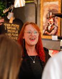 A costumed guide at Villains Rum of York leads a rum tasting inside a dimly lit shop filled with vintage decor and bottles. Guests smile and raise tasting glasses as they listen to stories of York’s historical villains.